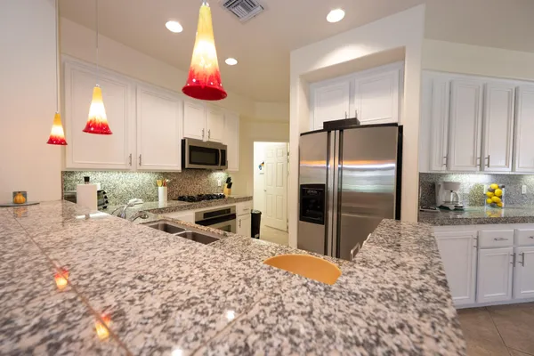 a kitchen with stainless steel appliances kitchen island granite countertop a refrigerator and a sink