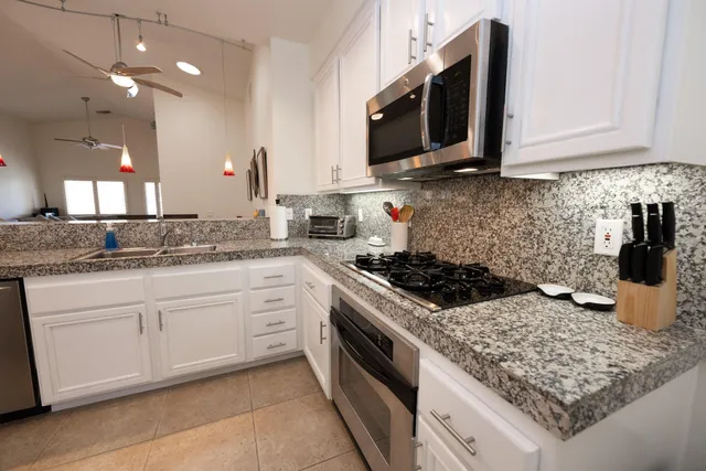 a kitchen with stainless steel appliances granite countertop a sink stove and microwave