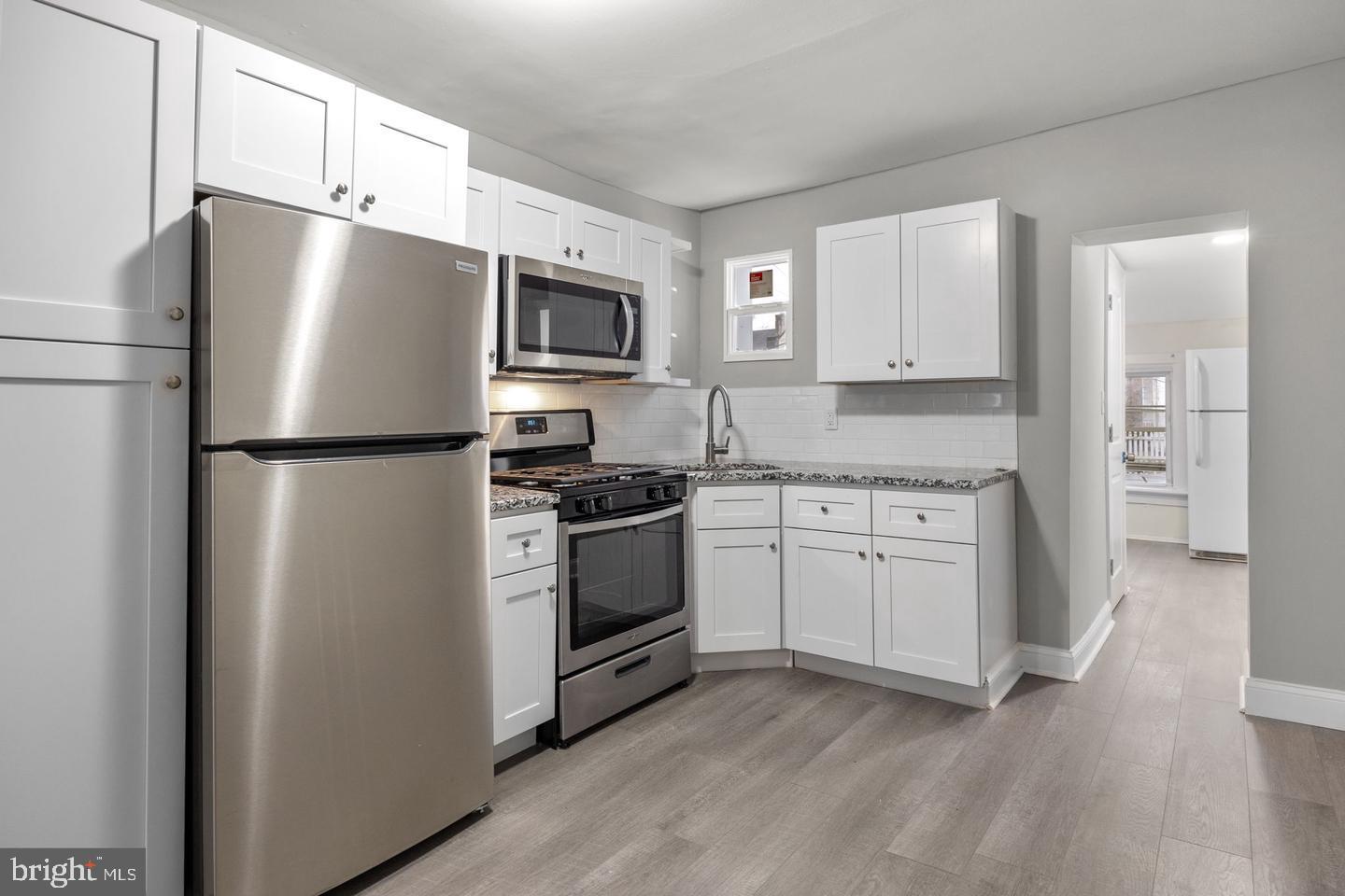 a kitchen with a refrigerator stove and white cabinets