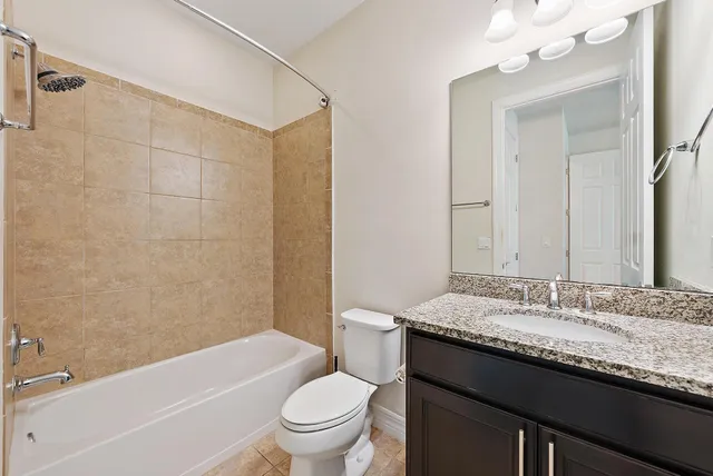 a bathroom with a granite countertop sink a toilet a mirror a bathtub and shower