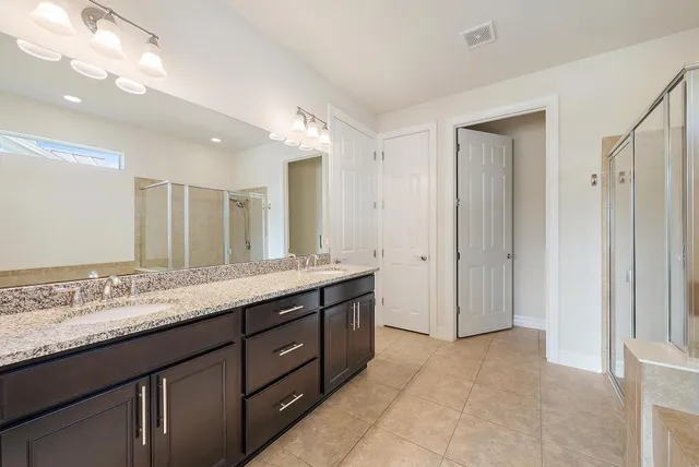 a bathroom with a granite countertop double vanity sink and mirror