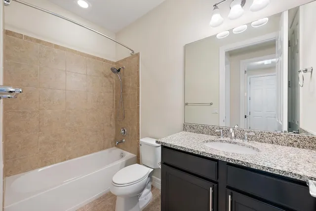 a bathroom with a granite countertop sink a toilet a mirror a bathtub and shower