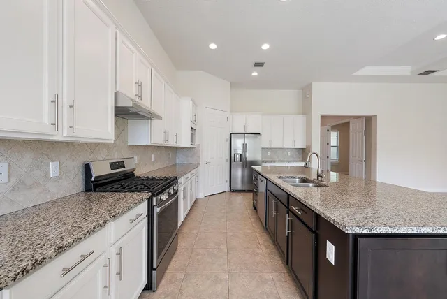 a kitchen with granite countertop kitchen island a sink stove and cabinets