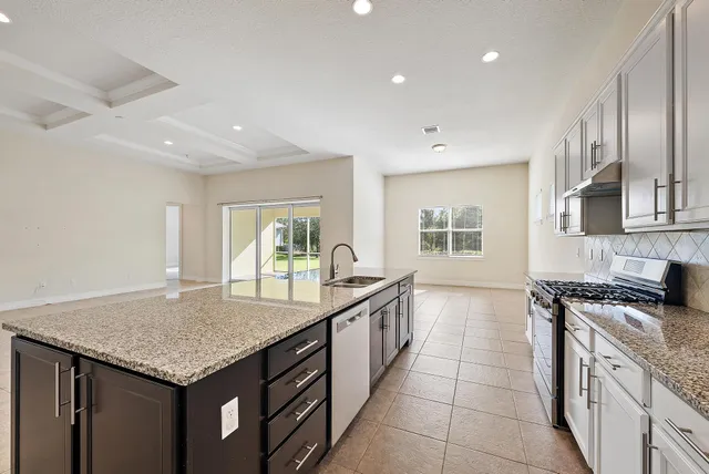 a kitchen with stainless steel appliances granite countertop a sink stove and cabinets