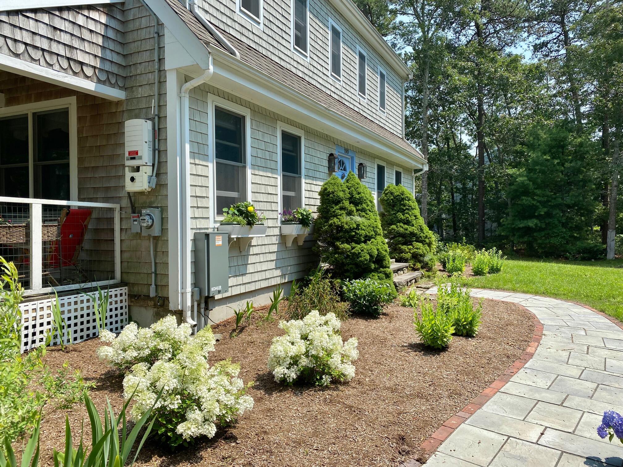 190 Little River Road Cotuit, MA 02635 - Photo 3 of 23 a front view of a house with a garden