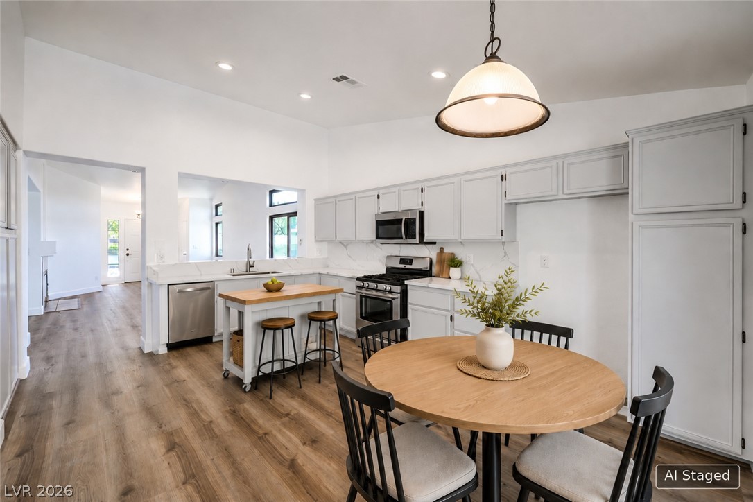 1900 Cardinal Point Street Henderson, NV 89012 - Photo 32 of 32 A pristine kitchen features ample white cabinetry, sleek countertops, and stainless steel appliances, all illuminated by recessed and pendant lighting.