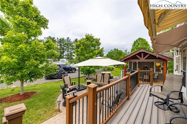 a view of a deck with a table and chairs under an umbrella with wooden fence