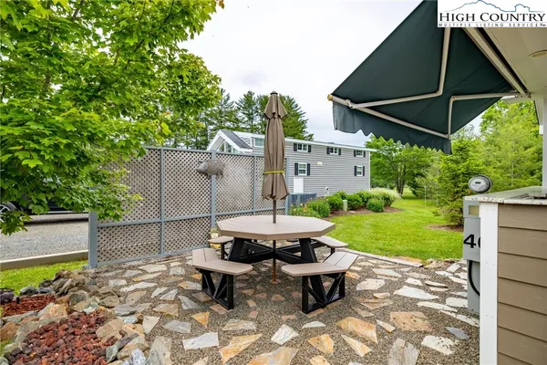 a backyard of a house with table and chairs under an umbrella