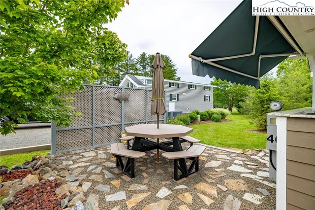 a backyard of a house with table and chairs under an umbrella
