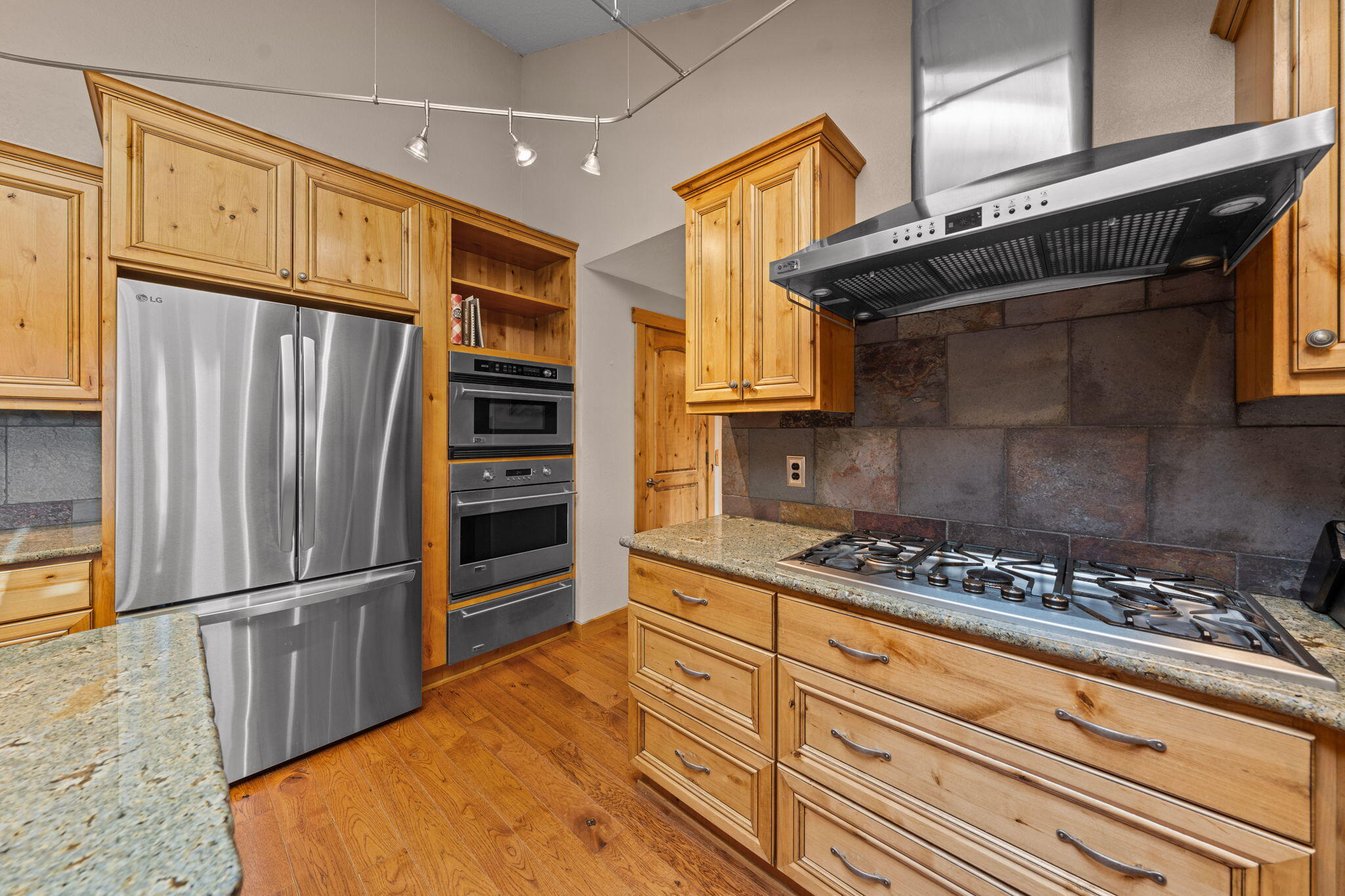 17375 Jordan Road Sisters, OR 97759 - Photo 21 of 63 Beautiful kitchen with upgraded cabinetry, under cabinet lighting, granite countertops, GE Monogram range, hood, and oven, and stainless steel refrigerator.