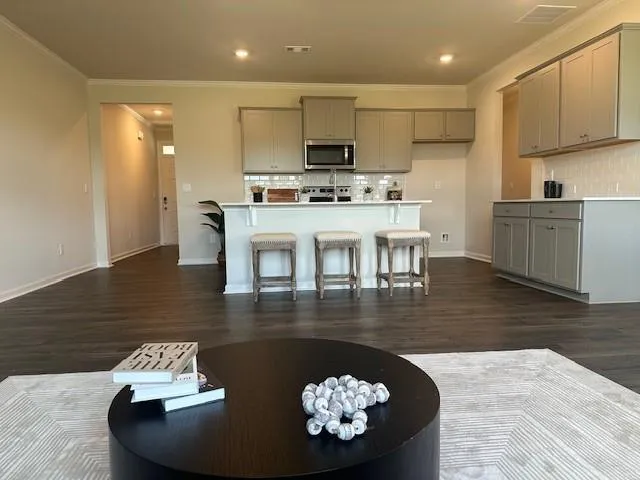 a kitchen with kitchen island granite countertop a stove a sink a refrigerator white cabinets and a dining table with wooden floor