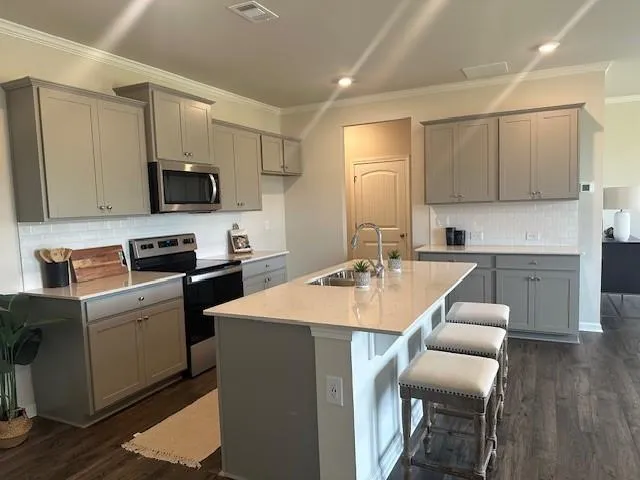 a kitchen with stainless steel appliances granite countertop a sink a stove a microwave a refrigerator a microwave oven and a refrigerator with wooden floor