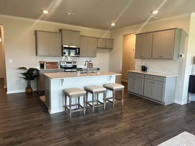 a kitchen with stainless steel appliances granite countertop a table chairs microwave and sink