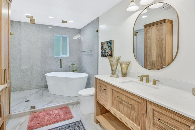 1350 Canyon Park Road Bountiful, UT 84010 - Photo 22 of 38 Spacious bathroom featuring a freestanding soaking tub, a walk-in shower with glass enclosure, a dual shower system, a wood-finish vanity with an integrated sink and gold-tone fixtures, and large-format tile flooring