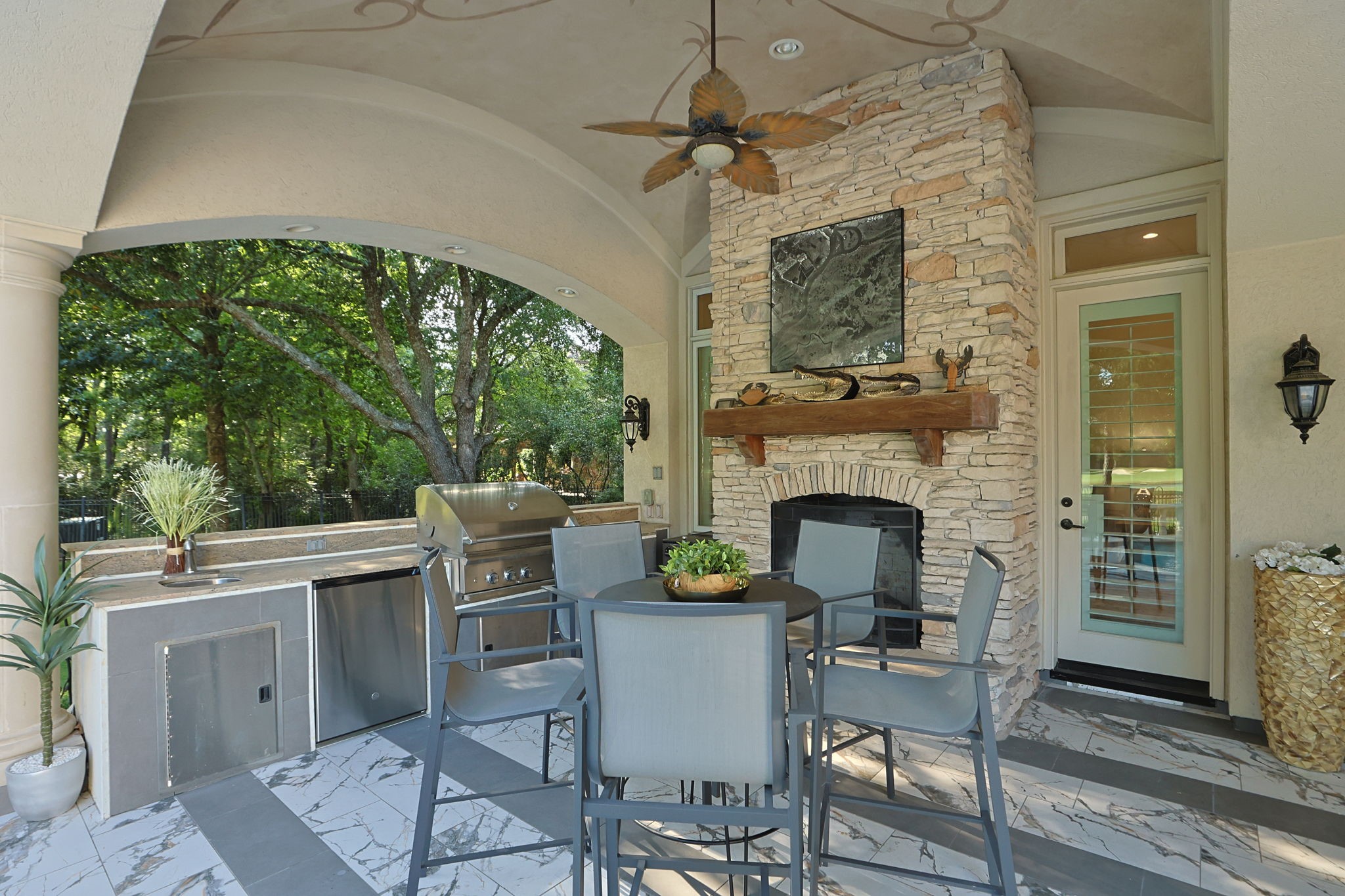 39 Maymont Way Spring, TX 77382 - Photo 38 of 50 This outdoor living space features a covered patio with a built-in grill, stylish seating, and a stone fireplace. It offers a serene view of lush greenery, perfect for entertaining or relaxing.