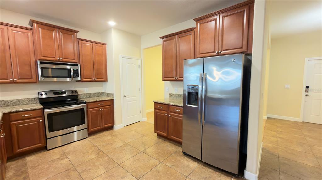 13040 Overstreet Road Windermere, FL 34786 - Photo 12 of 45 a kitchen with granite countertop a refrigerator stove and microwave