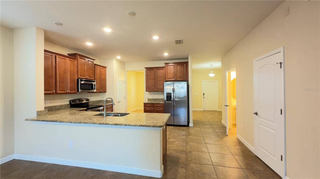 13040 Overstreet Road Windermere, FL 34786 - Photo 13 of 45 a view of a kitchen with kitchen island granite countertop a refrigerator and cabinets