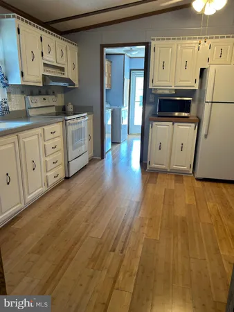 a kitchen with granite countertop a refrigerator a sink dishwasher and white cabinets with wooden floor