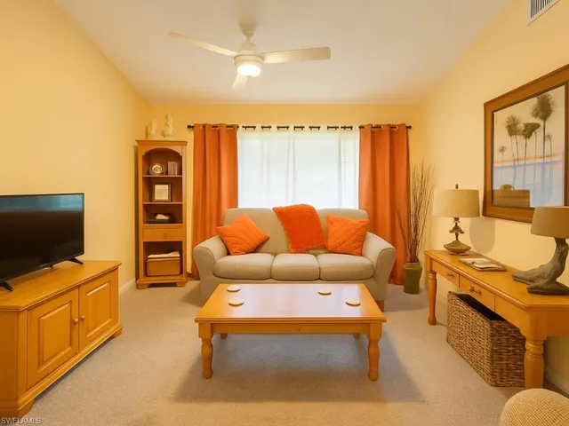 a living room with furniture a flat screen tv and a floor to ceiling window