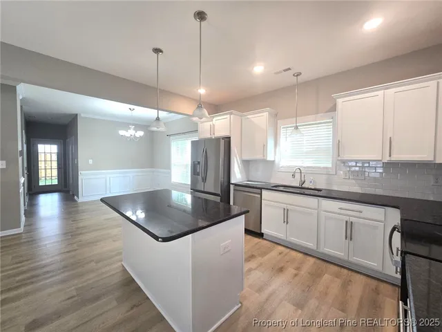 a kitchen with stainless steel appliances granite countertop a sink a stove top oven a counter space and a window