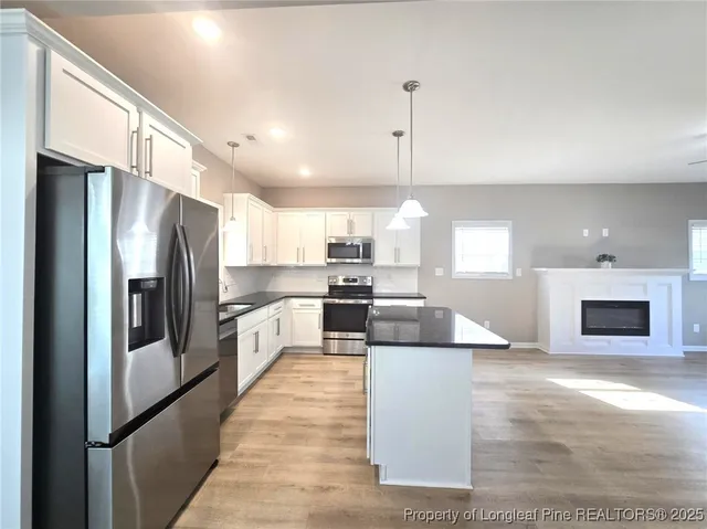 a large kitchen with kitchen island a large counter top stainless steel appliances and cabinets