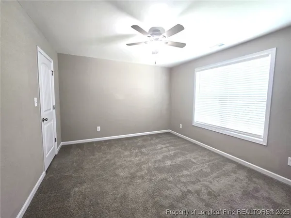 an empty room with a window and a fan
