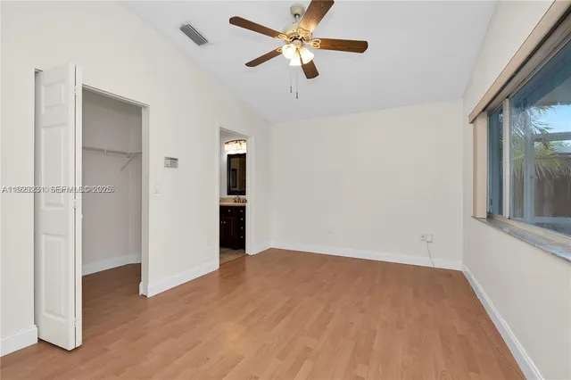 an empty room with closet and a ceiling fan