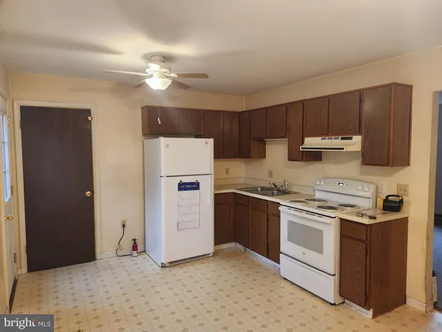 a kitchen with stainless steel appliances granite countertop a stove a refrigerator and a sink with wooden cabinets