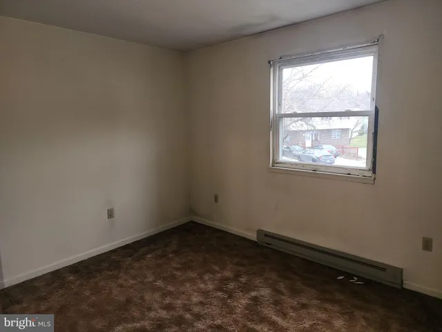 a view of an empty room with closet and a bathroom