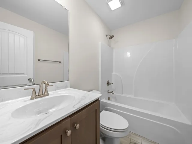 a bathroom with a granite countertop sink a toilet and shower