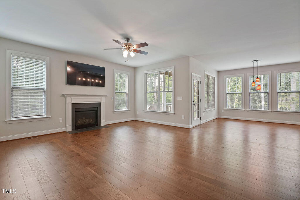 1124 Armsleigh Court Raleigh, NC 27603 - Photo 9 of 33 an empty room with wooden floor fireplace and windows
