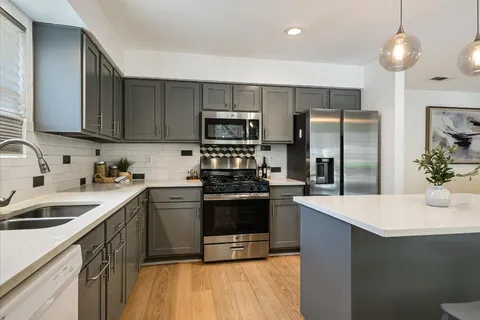 a kitchen with stainless steel appliances a sink a stove a refrigerator and cabinets