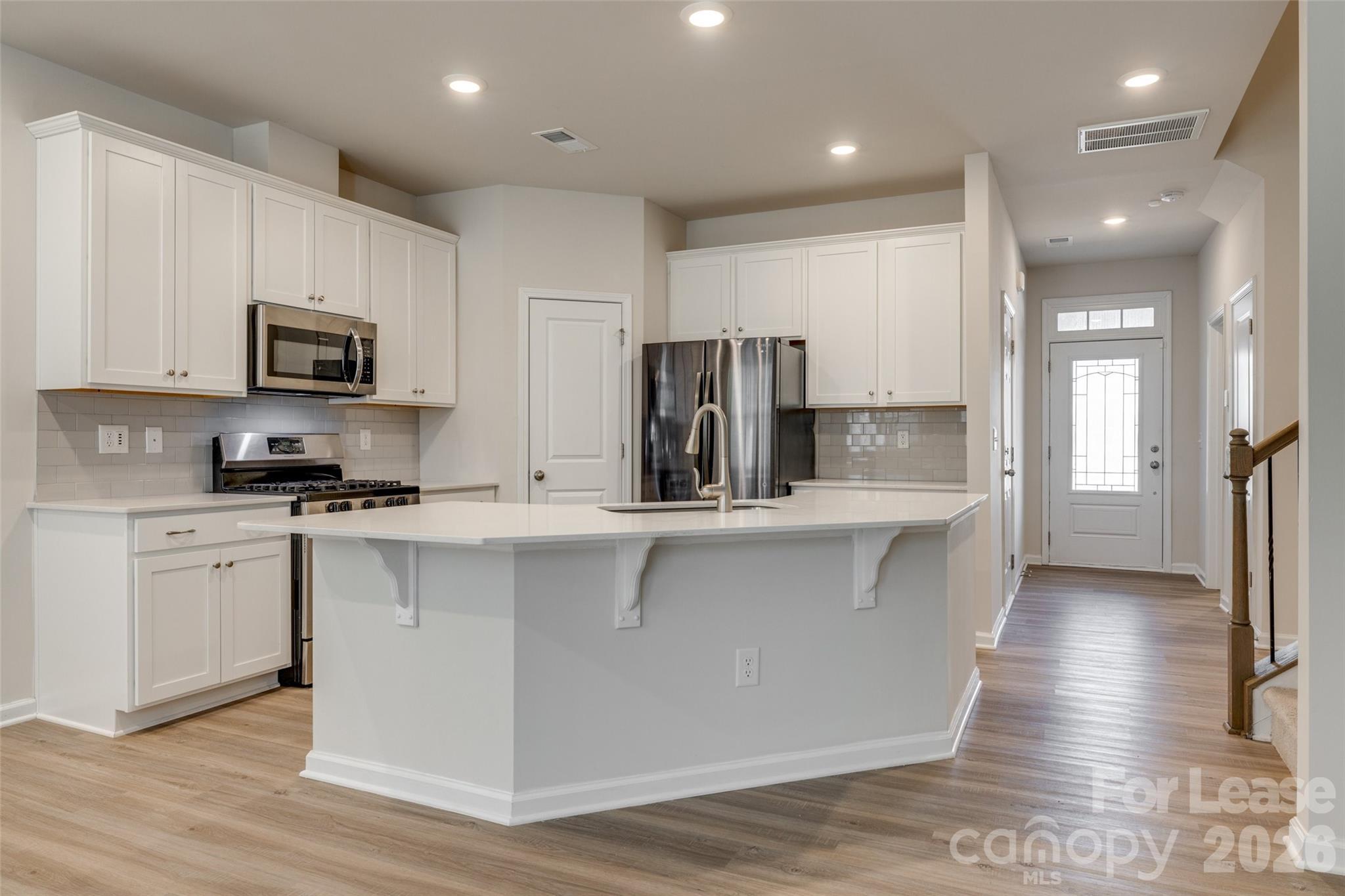 807 Gable Oak Lane Fort Mill, SC 29708 - Photo 5 of 39 a kitchen with kitchen island granite countertop a stove top oven a sink a refrigerator and white cabinets with wooden floor