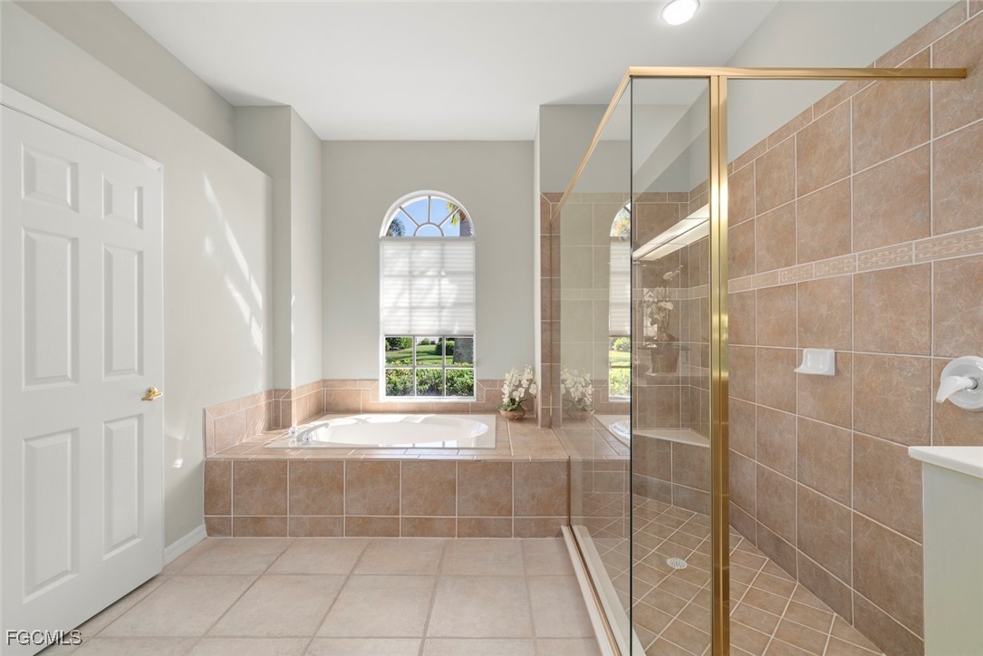 23180 Whispering Ridge Drive Estero, FL 34135 - Photo 25 of 42 a bathroom with a bathtub and a shower