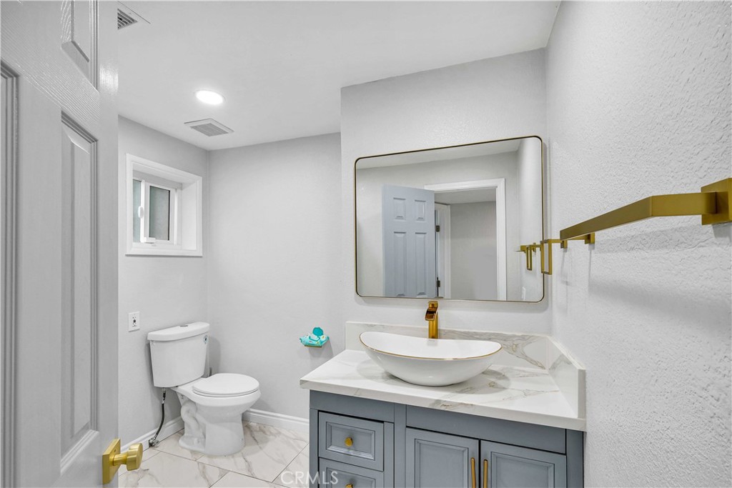 35716 Wildwood Canyon Road Yucaipa, CA 92399 - Photo 36 of 57 a bathroom with a granite countertop sink toilet and mirror