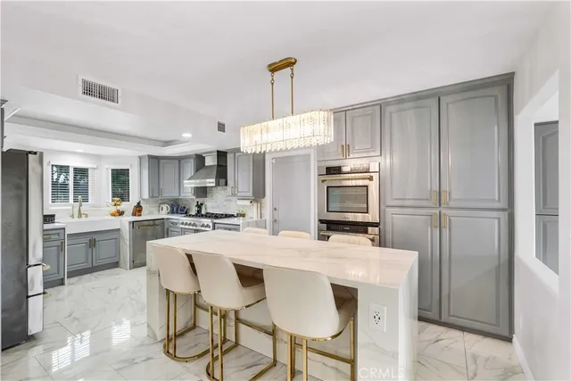 a kitchen with kitchen island a stove a chandelier and a refrigerator