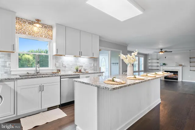 a kitchen with stainless steel appliances granite countertop white cabinets sink and dishwasher a stove with wooden floor