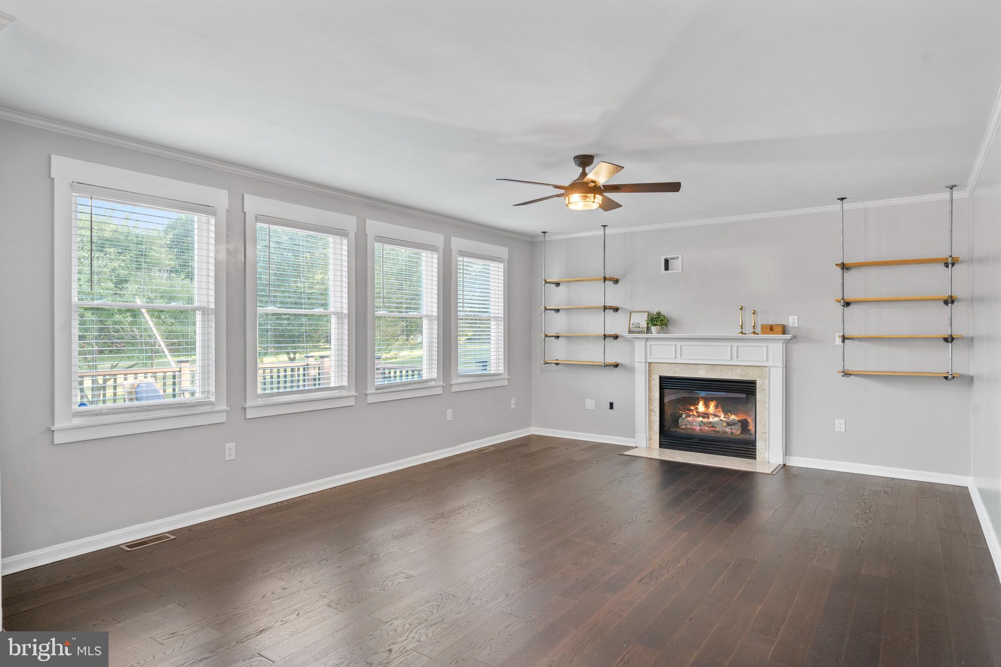 3446 Chaneyville Road Owings, MD 20736 - Photo 29 of 74 an empty room with windows a fireplace and wooden floor
