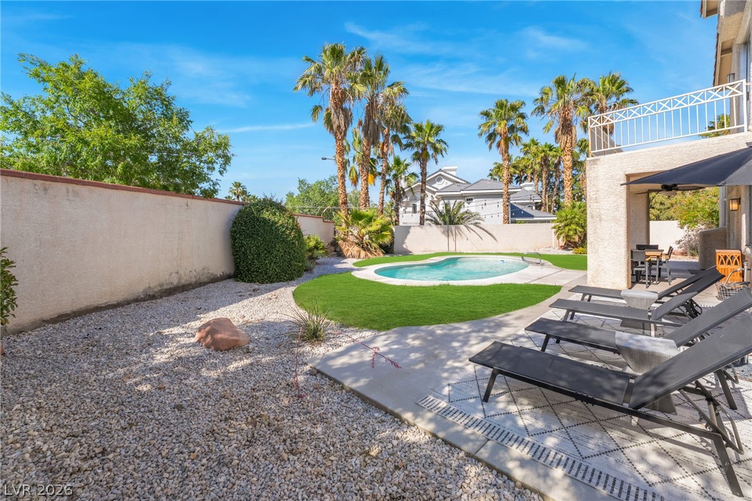 1941 Ivy Point Lane Las Vegas, NV 89134 - Photo 19 of 21 This private outdoor space features a refreshing pool, ample lounge areas, and mature palm trees under a bright sky.
