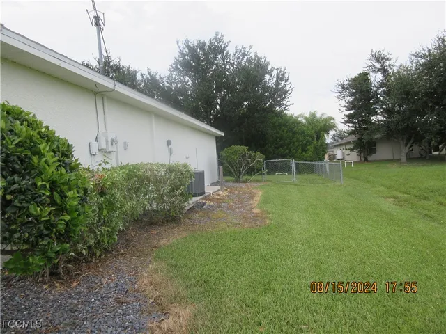 a backyard of a house with plants and large trees