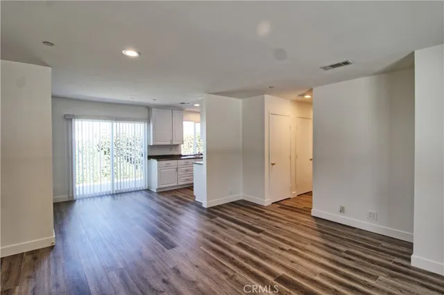 a view of a big room with wooden floor and a kitchen