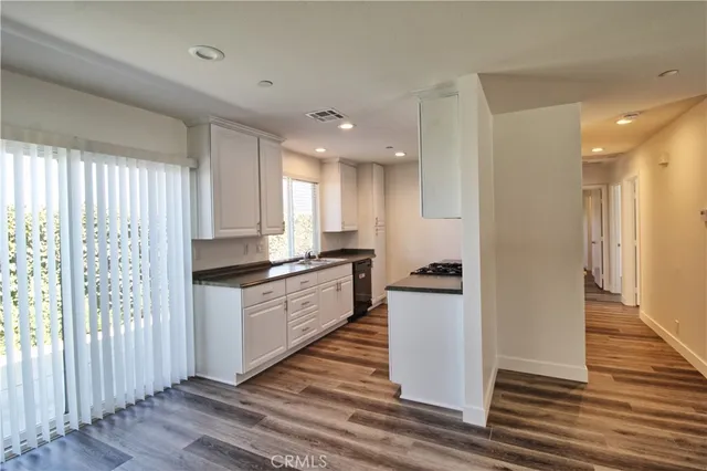 a kitchen with granite countertop a refrigerator and wooden floor