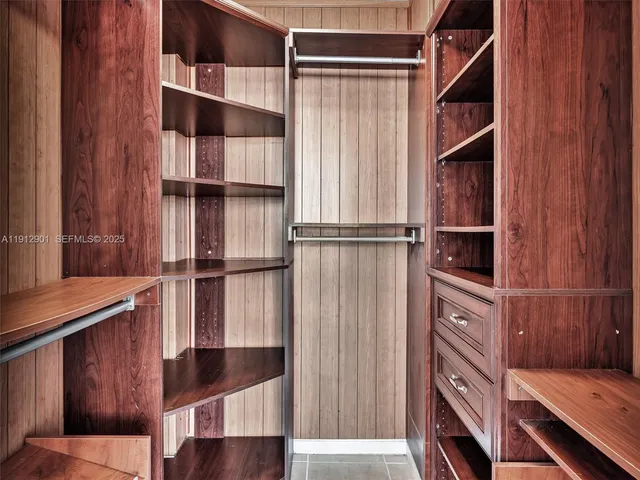 a view of an empty room with wooden floor and kitchen