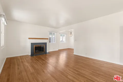 a view of empty room with wooden floor and fireplace