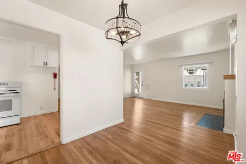 a view of a room with wooden floor staircase and a kitchen space