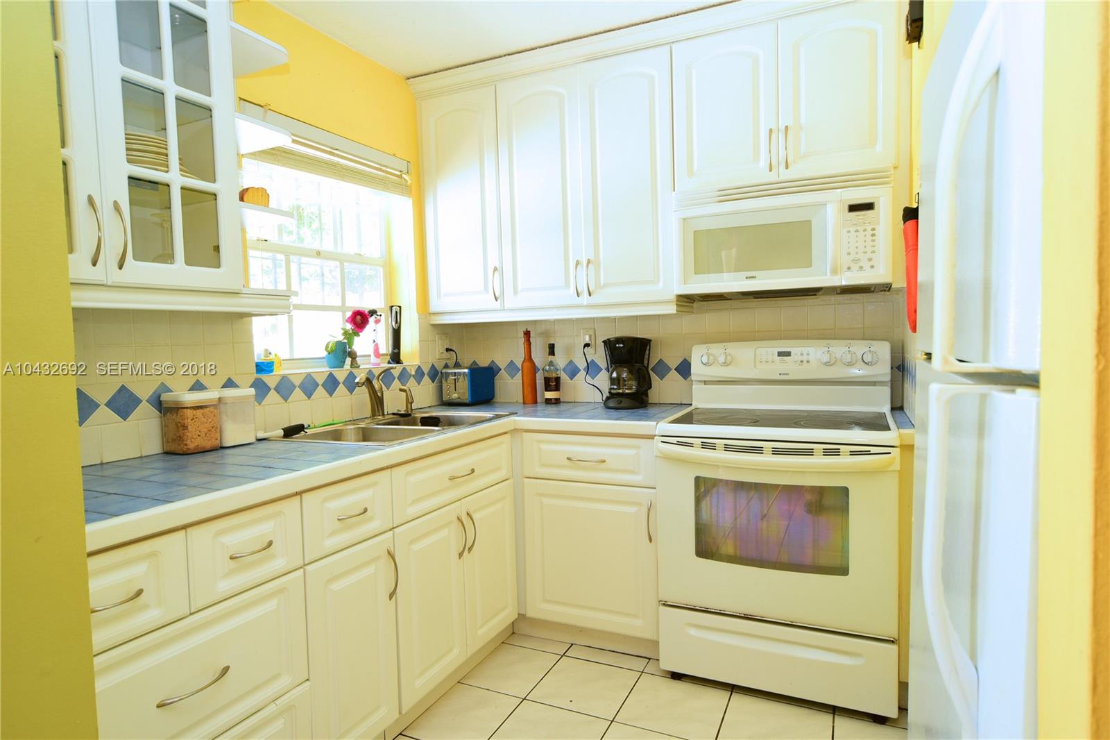 12193 Southwest 10th Street, Unit 1 Miami, FL 33184 - Photo 3 of 16 a kitchen with white cabinets and white appliances