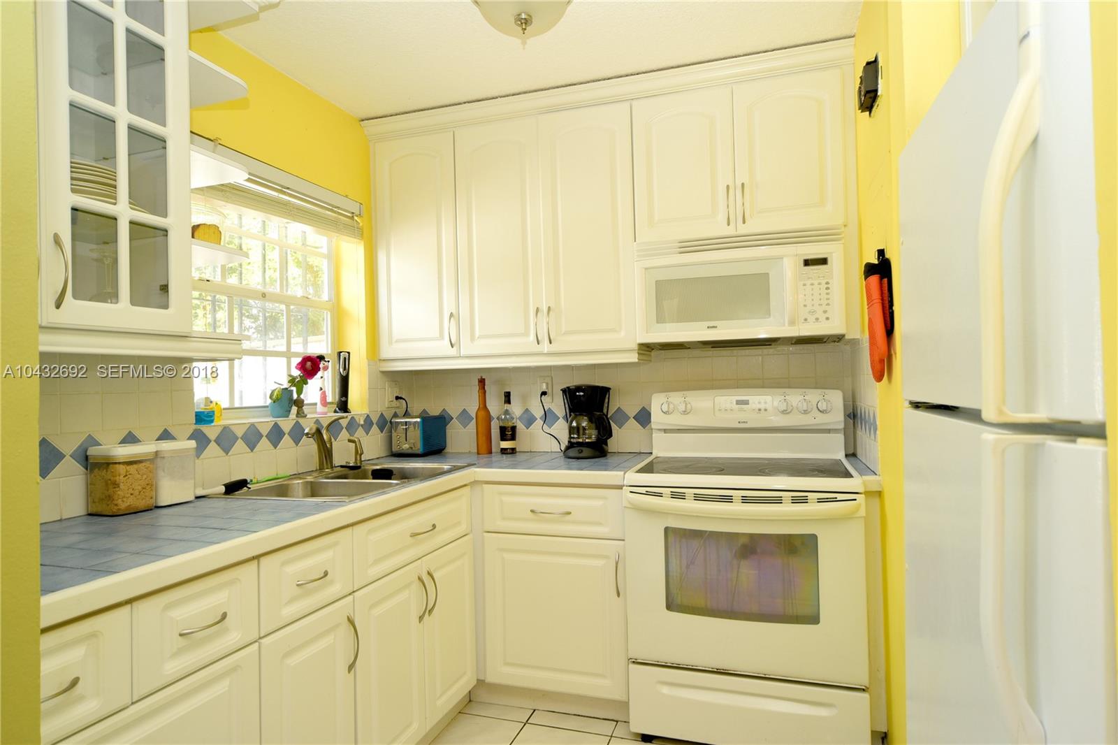 12193 Southwest 10th Street, Unit 1 Miami, FL 33184 - Photo 7 of 16 a kitchen with stainless steel appliances white cabinets and a refrigerator