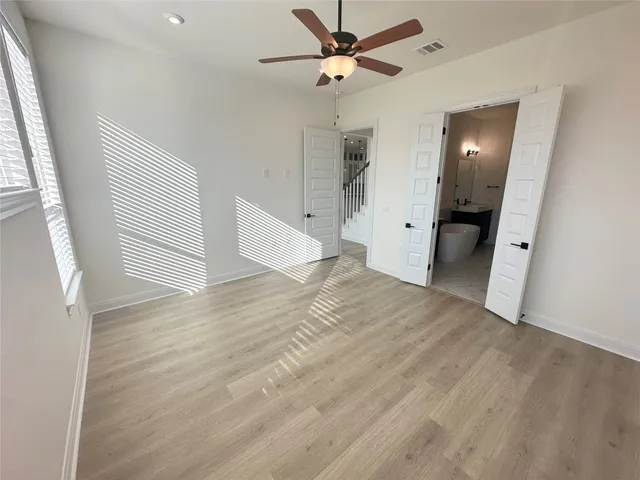 a view of empty room with wooden floor and fan