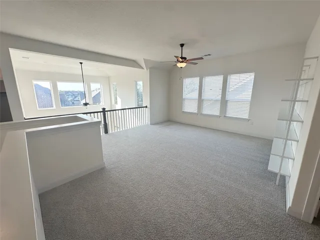 an empty room with chandelier fan and windows