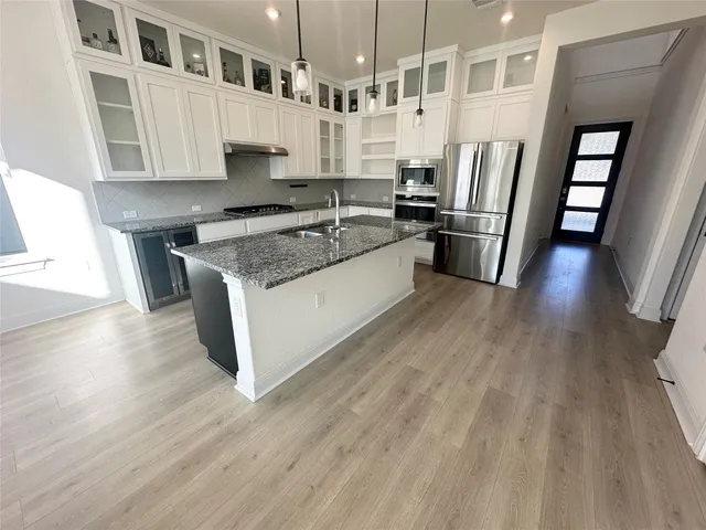 a large kitchen with stainless steel appliances granite countertop a stove a sink dishwasher a refrigerator and cabinets with wooden floor